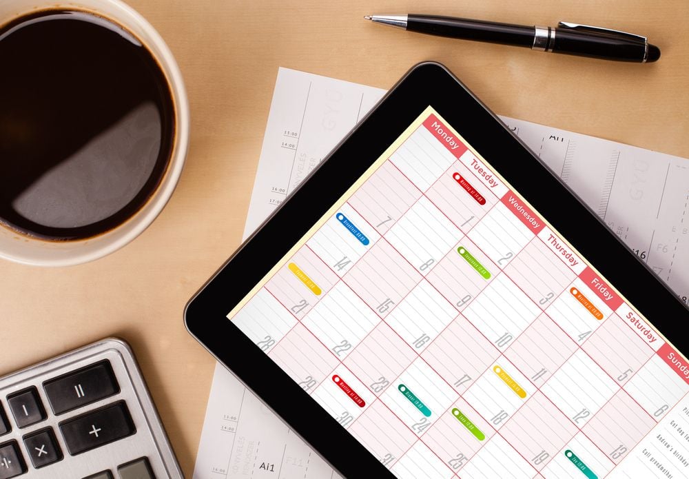 Workplace with tablet pc showing calendar and a cup of coffee on a wooden work table close-up-2